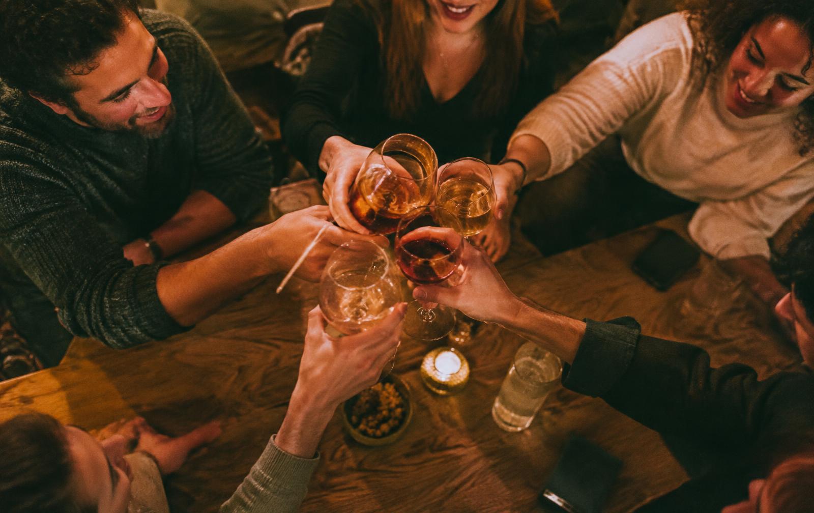 Friends raising glasses together over a shared table